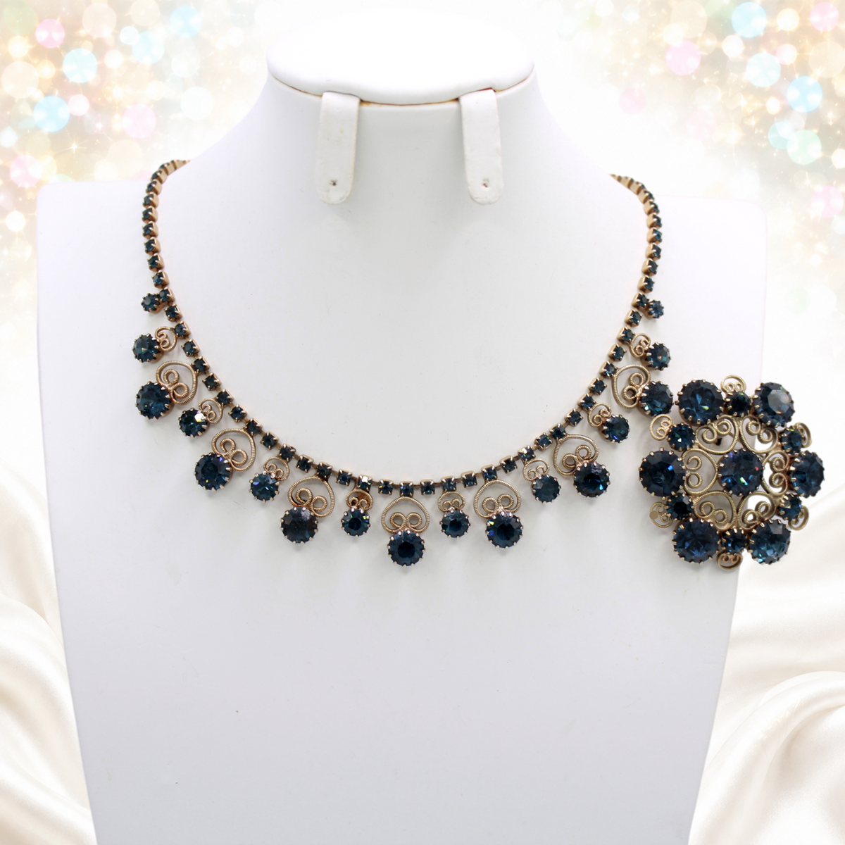 Close-up of graduated dark blue rhinestone necklace with heart scrollwork and circular brooch