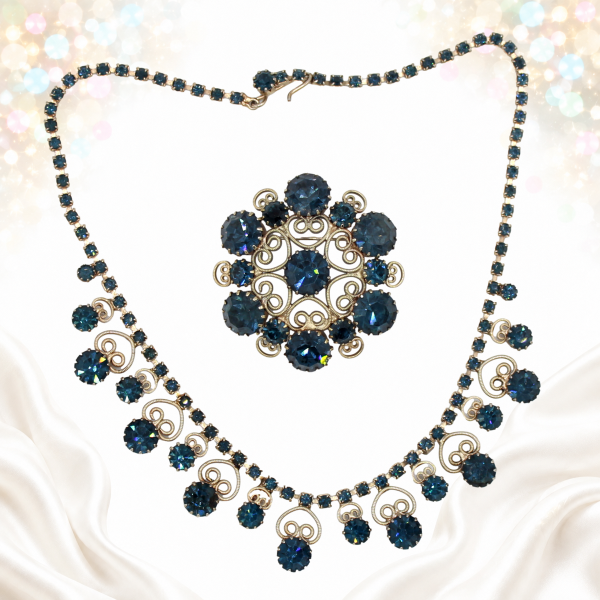 Dark blue rhinestone Juliana necklace and round scrollwork brooch displayed separately