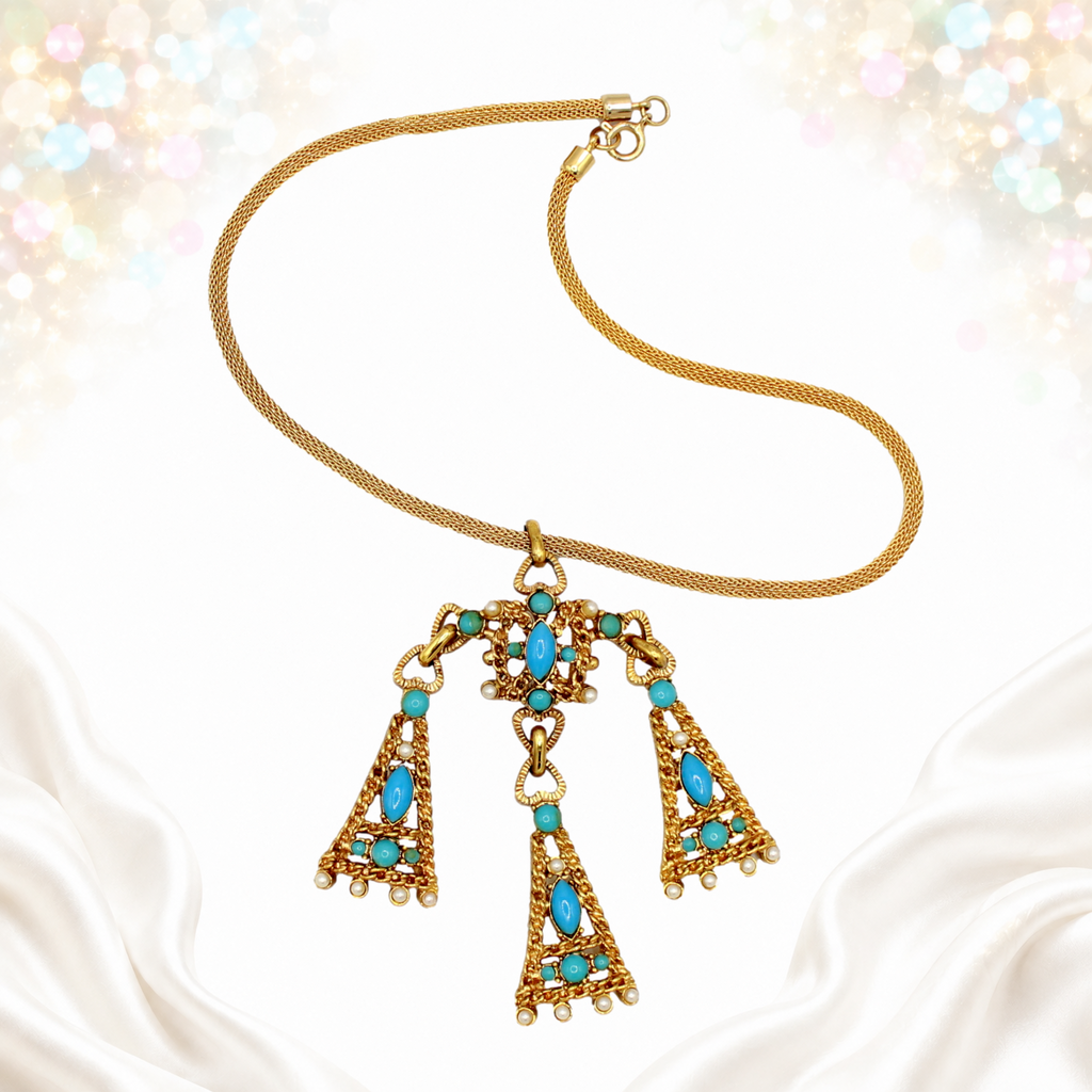 Pendant necklace laid flat showing turquoise-colored cabochons and faux pearl-like accents