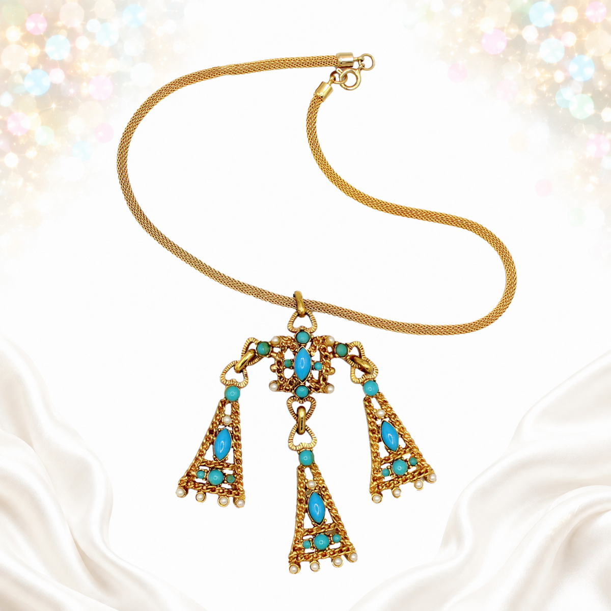Pendant necklace laid flat showing turquoise-colored cabochons and faux pearl-like accents