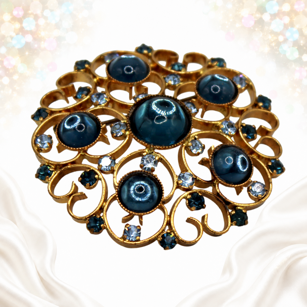 Angled detail showing domed blue Lucite cabochons and gold-tone heart scrollwork