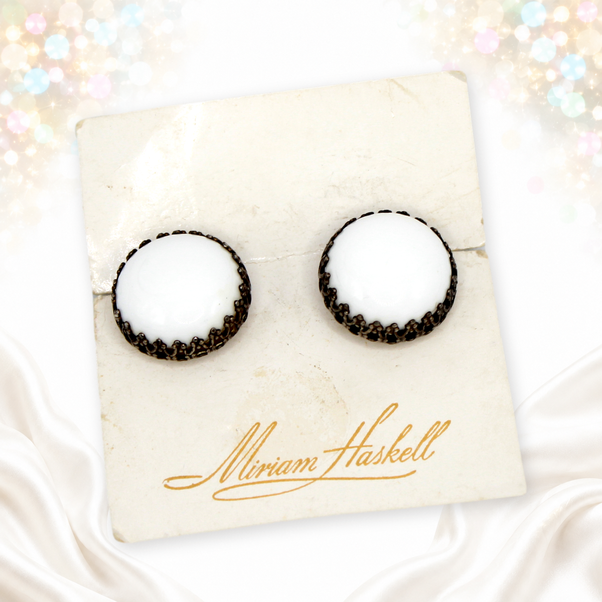 Angled photo of Miriam Haskell white round cabochon vintage clip earrings