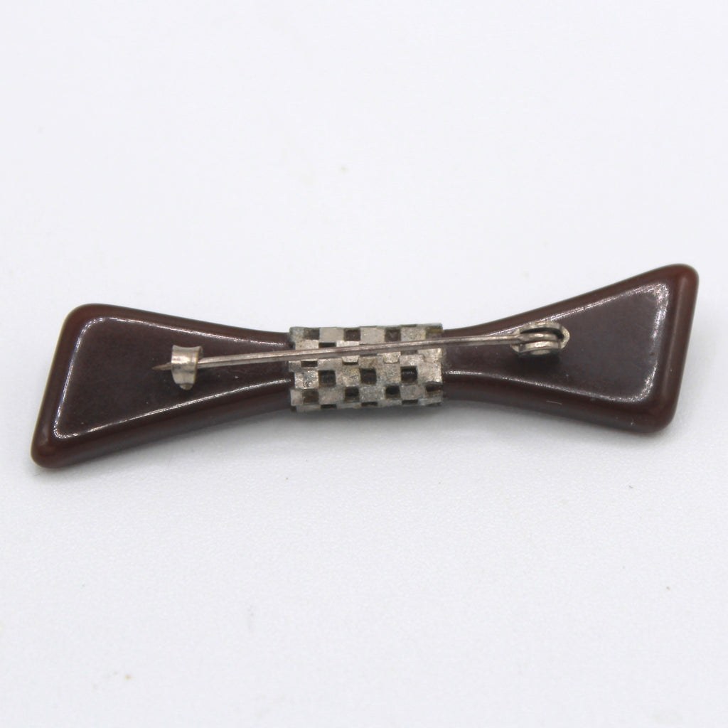 Back of brown Bakelite bow brooch showing silver checkerboard openwork band and C clasp