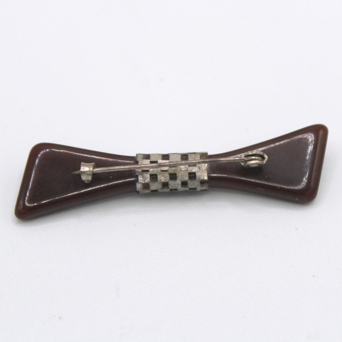 Back of brown Bakelite bow brooch showing silver checkerboard openwork band and C clasp