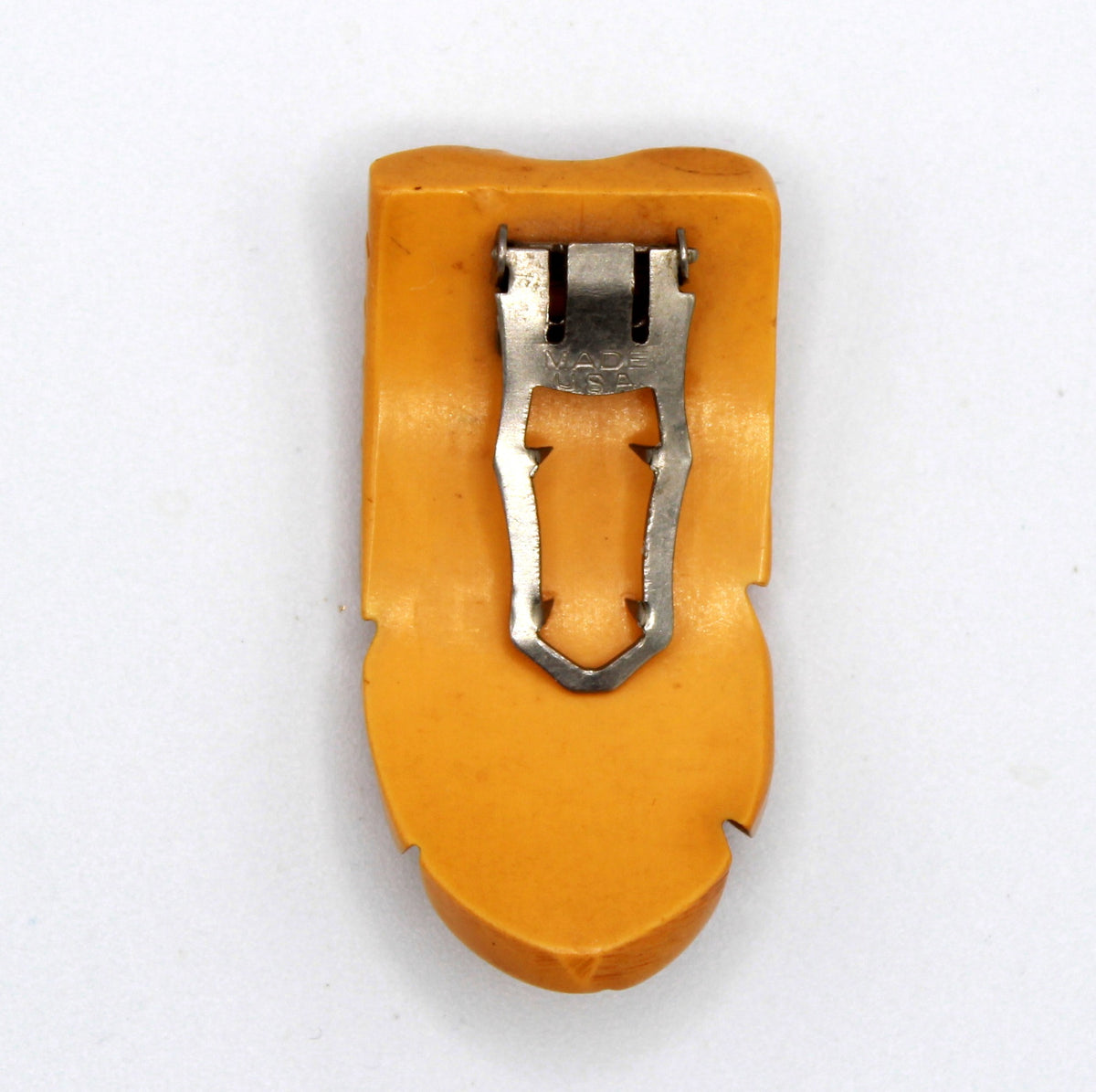 Back view of vintage carved butterscotch Bakelite dress clip with MADE USA metal clip