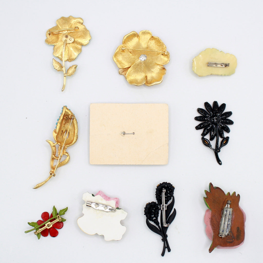 Back view of the same ten vintage brooches showing their pin fastenings and flower basket display card
