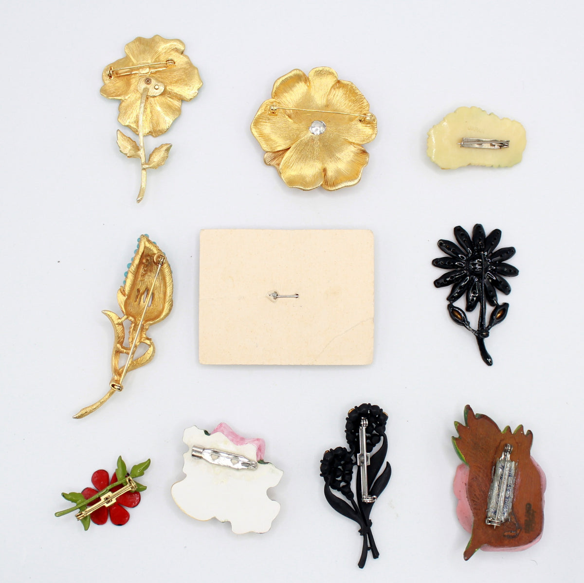 Back view of the same ten vintage brooches showing their pin fastenings and flower basket display card