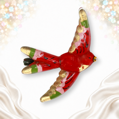 Red reverse-painted plastic flying bird brooch with gold, pink and green accents