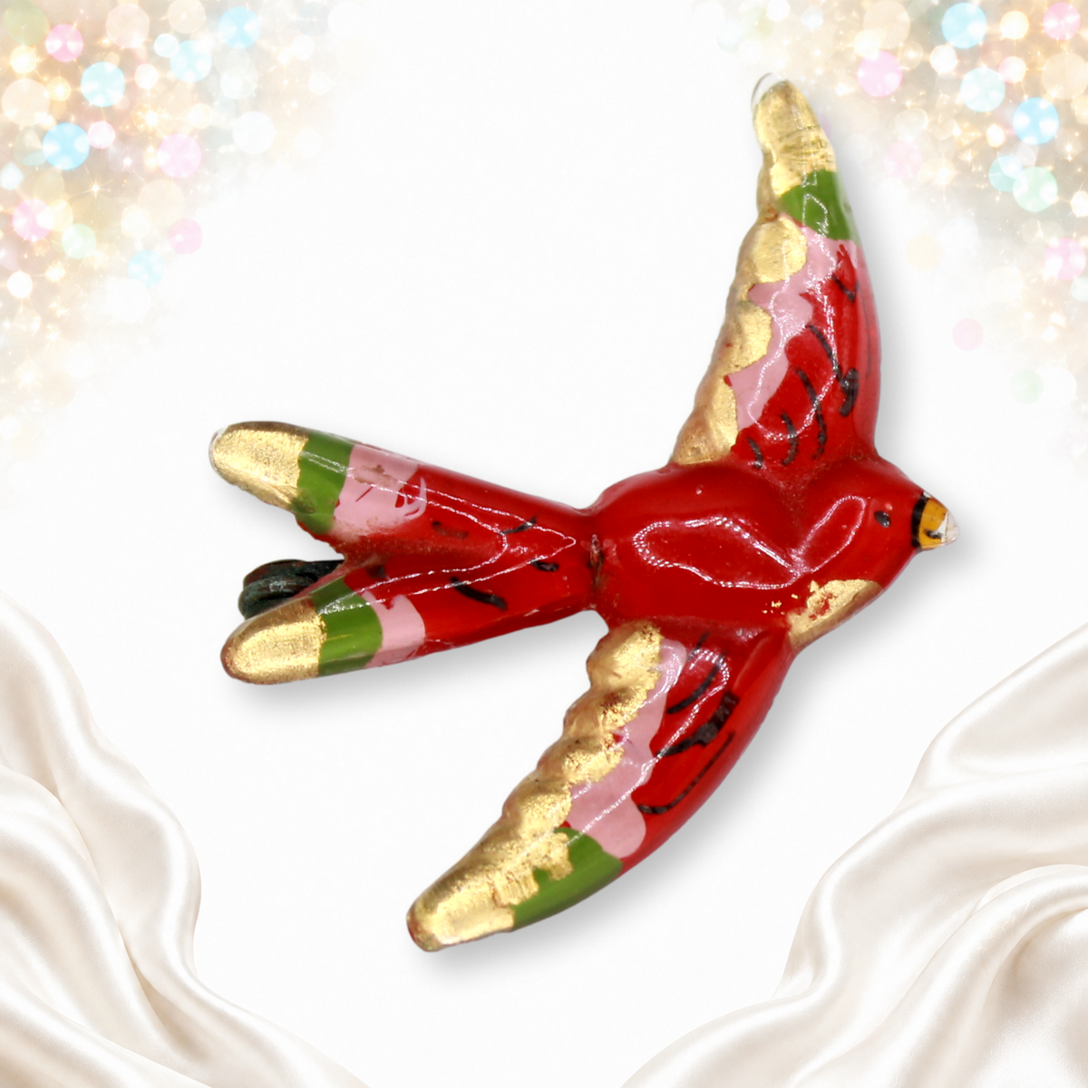 Red reverse-painted plastic flying bird brooch with gold, pink and green accents